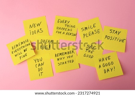 Paper notes with life-affirming phrases on pink background