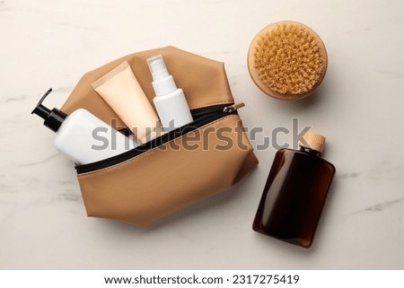 Preparation for spa. Compact toiletry bag and different cosmetic products on white marble table, flat lay Royalty-Free Stock Photo #2317275419