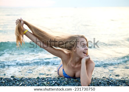 Beautiful girl with long thick white hair resting on the beach a summer day