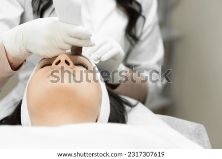 Individual approach to the skin: a professional cosmetologist takes into account the unique needs of the patient's skin, using ultrasonic facial cleansing as an individual approach to facial skin care Royalty-Free Stock Photo #2317307619