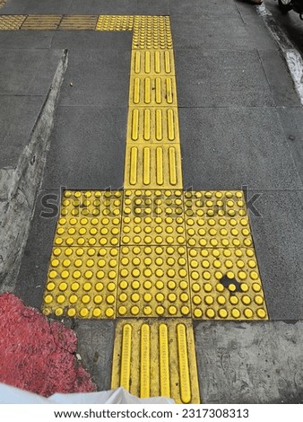 Guiding block for disability. Bright yellow tactile paving for the visually impaired on the sidewalk.