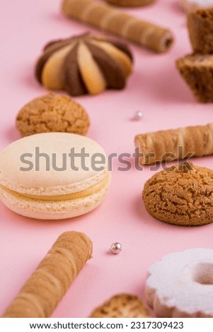 Sweet selection of patisserie on pink background. Macaron, meringue, biscuit, amaretto pastry, tea time candy.