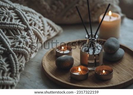 Apartment natural aroma diffusor with sea breeze fragrance. Burning candles on bamboo tray, cozy home atmosphere. Relaxation, detention zone in the living or bedroom. Stones as decor Royalty-Free Stock Photo #2317322159