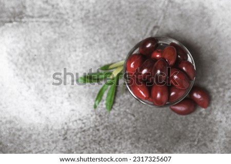 Red olives on a marble background. Various types of olives in bowls and olive oil with fresh olive leaves. Copy space. Place for text. Mediterranean food. Vegan.