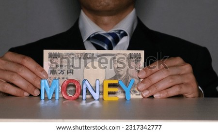 Businessman with 10000 yen bill.

Translation: Bank of Japan notes, 10000 yen, Bank of Japan, kichi.