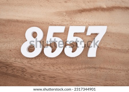 White number 8557 on a brown and light brown wooden background.