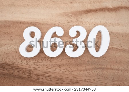 White number 8630 on a brown and light brown wooden background.