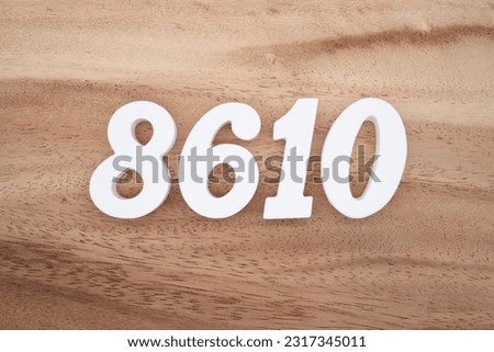 White number 8610 on a brown and light brown wooden background.