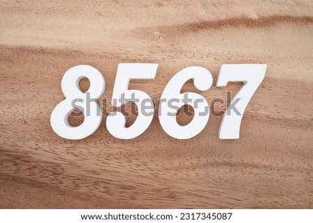 White number 8567 on a brown and light brown wooden background.
