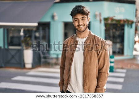 Young hispanic man smiling confident standing at street Royalty-Free Stock Photo #2317358357