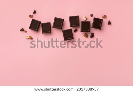 World Chocolate Day, july 07.  Dark chocolate bar pieces with nuts on pink background, top view, copy space. Holiday greeting card or banner concept.