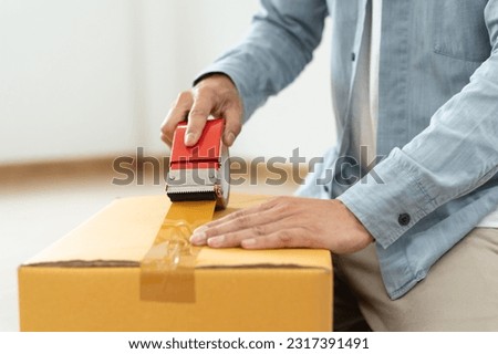 family relocation to new place concept, close up hands of person using tape packing cardboard of belonging stuff preparation to moving out relocation. Royalty-Free Stock Photo #2317391491