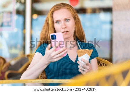 Woman surprised by something she is looking at with her smartphone Royalty-Free Stock Photo #2317402819