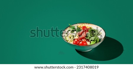 Banner of Asian poke bowl with tuna, avocado, and edamame served in a bowl, against a green monochromatic background. Modern minimalist presentation with copy space.