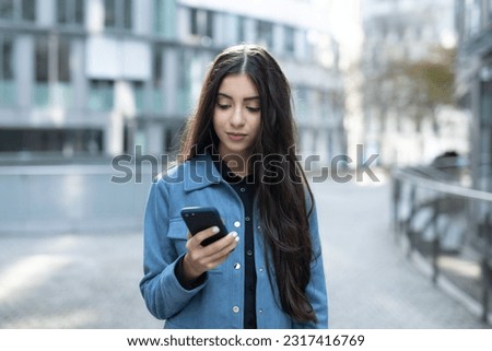 teen girl with smart mobile phone stand in urban city look to cellphone in her hand and touch to display while being addicted to social media and feel nomophobia