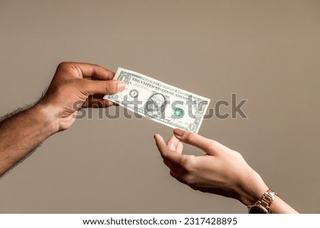 Hand of a young man giving one dollar to a women. Royalty-Free Stock Photo #2317428895