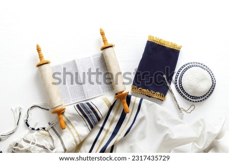 Torah scroll with a pointer, prayer shawl tallit and kippah on a light background Royalty-Free Stock Photo #2317435729