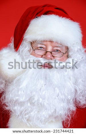 Close-up portrait of Santa Claus. Christmas time. Red background.