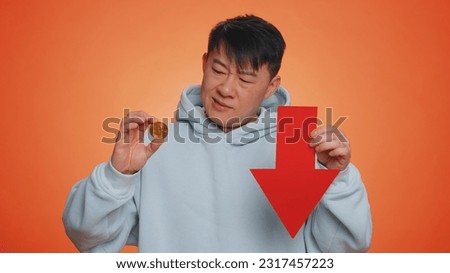 Asian man show golden bitcoins indicating red arrow banner down sign, decrease of exchange rate. Unsuccessful bankruptcy business, fall of stock cryptocurrency market investment mining BTC technology