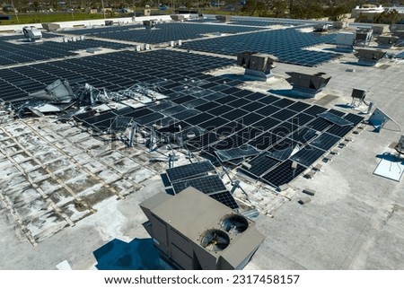 Aerial view of damaged by hurricane wind photovoltaic solar panels mounted on industrial building roof for producing green ecological electricity. Consequences of natural disaster Royalty-Free Stock Photo #2317458157