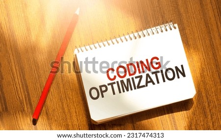 CODING OPTIMIZATION on yellow notebook with red marker and wooden background