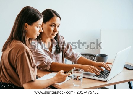 Young women working and communicating together in a creative office. Successful feminine teamwork and business brainstorming concept.