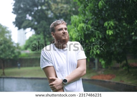 Sad frozen man under summer rain.emotional wet in the rain without umbrella walk in the rain.young attractive guy is wet in the rain Royalty-Free Stock Photo #2317486231