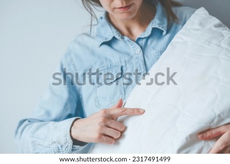 Faceless female pointing finger bed bugs on a white pillow. Health problems and sleep disorders. High quality photo