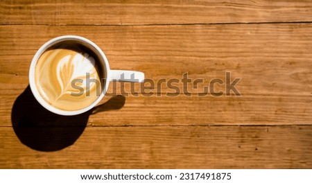 Aerial view of a wooden table with a cup of coffee on one side, perfect for writing text. Cafeteria and breakfast concept