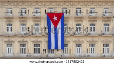 A frontal photo of a facade of a hotel in Havana - Cuba with Cuban flag