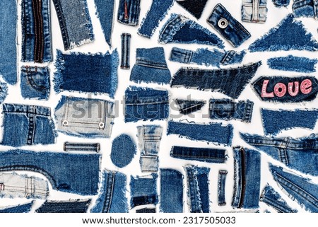 Love Denim Jean background. Destroyed torn denim jeans fabric pieces on white background, flat lay. Recycle old jeans denim concept. Royalty-Free Stock Photo #2317505033