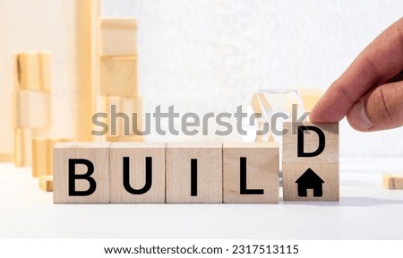 Time to rebuild symbol. Turned wooden cubes and changes the word 'build' to 'rebuild'. Beautiful grey table, blue background. Business, build or rebuild concept. Copy space.