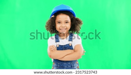 Little girl, face and smile in construction on green screen with safety helmet and arms crossed against a studio background. Portrait of small and happy child architect smiling on chromakey mockup