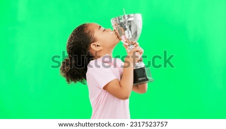 Celebration, win and face of child with trophy isolated on a green screen studio background. Excited, success and portrait of a girl kissing an award for sports, achievement and champion with mockup