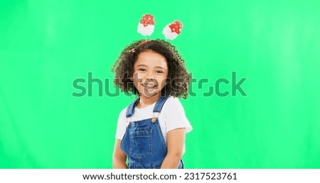 Portrait, children and cute with a girl on a green screen background in studio wearing a funky alice band. Kids, smile and innocent with an adorable little female child standing on chromakey mockup