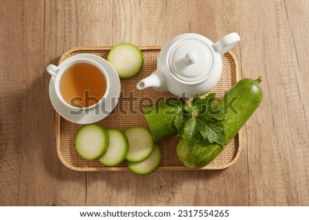White teapot and a cup containing tea are arranged on bamboo tray with winter melon. Winter melon tea has the main ingredient is water, no fat and very low sodium content Royalty-Free Stock Photo #2317554265
