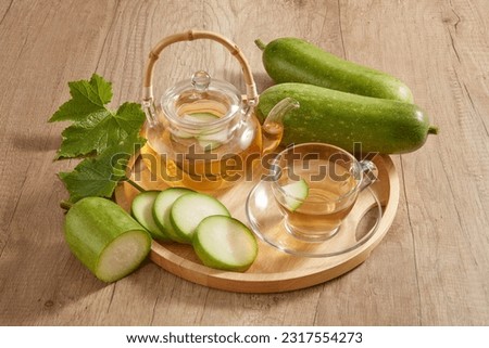 A wooden tray in round-shaped with a transparent tea set and fresh green winter melon placed on. Winter melon (Benincasa hispida) is a very good cooling drink Royalty-Free Stock Photo #2317554273