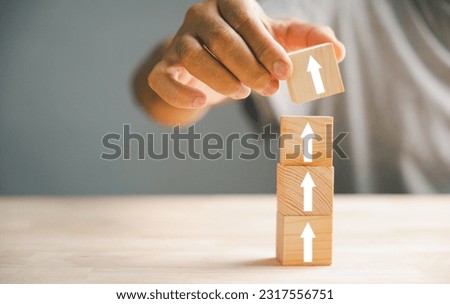 Hand arranging wood block stacking step stair with an upward arrow. Ladder career path for business growth and success process concept. Build your way up for increased revenue and personal development Royalty-Free Stock Photo #2317556751