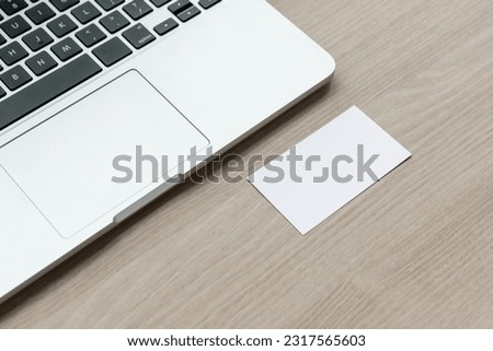 A laptop on a conference room table and a horizontal business card handed over. blank card , mockup