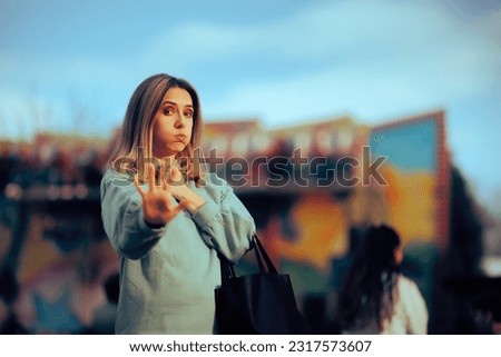 
Woman Making Stop Hand Sign Gesture in a Funfair 
Person trying to push back in a crowded public space 
 Royalty-Free Stock Photo #2317573607