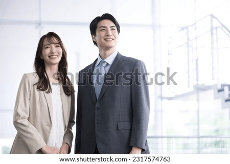 Two Japanese company employees, male and female, in their 20s and 30s, wearing suits. The photo fits the image of a mid-career change, such as mid-career hiring. Royalty-Free Stock Photo #2317574763