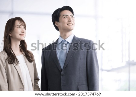 Two Japanese company employees, male and female, in their 20s and 30s, wearing suits. The photo fits the image of a mid-career change, such as mid-career hiring. Royalty-Free Stock Photo #2317574769