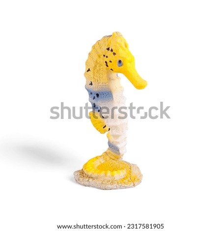 Close-up of a yellow sea horse toy miniature side view against a white background