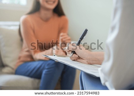 Psychology, depression. smile asian young woman, female patient mental explained symptom with psychologist, psychiatrist while doctor woman taking notes at clinic. Encouraging, therapy. Royalty-Free Stock Photo #2317594983