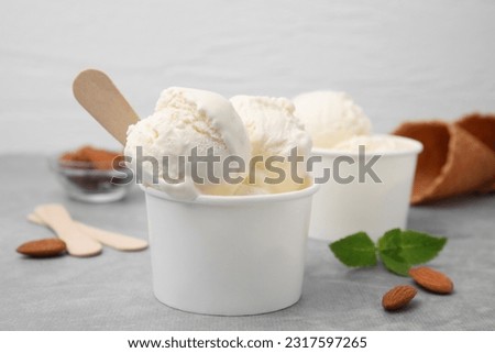 Delicious vanilla ice cream in paper cup on light grey table