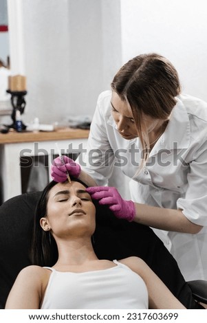 Beautician is injecting botulinum toxin to correct mimic wrinkles and hyperhidrosis for young girl. Botulinum toxin to relax and neutralize overactive muscles that cause wrinkles Royalty-Free Stock Photo #2317603699