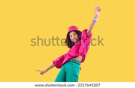 Cheerful dark-skinned teenage girl laughing, having fun and fooling around on yellow background. Stylish smiling ethnic kid girl in fashionable youth bright colored clothes. Children's fashion concept