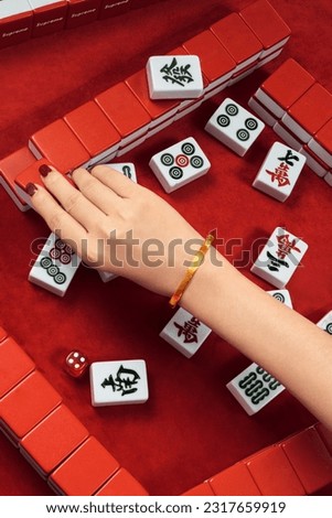 Woman in cheongsam playing mahjong(majiang), close-up, traditional Chinese mind game(Translation: mahjong terms, east, west, south, north, middle, fortune)