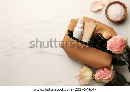 Preparation for spa. Compact toiletry bag, flowers and different cosmetic products on white marble table, flat lay with space for text Royalty-Free Stock Photo #2317674647