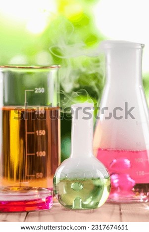 Laboratory glassware with colorful liquids on wooden table outdoors. Chemical reaction